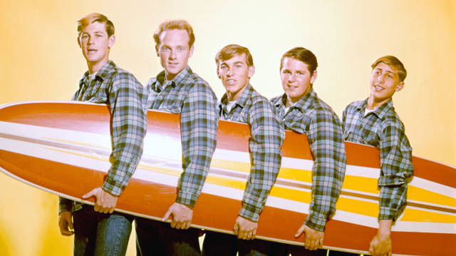 The Beach Boys pose for a portrait with a surfboard in August 1962 in Los Angeles, California
